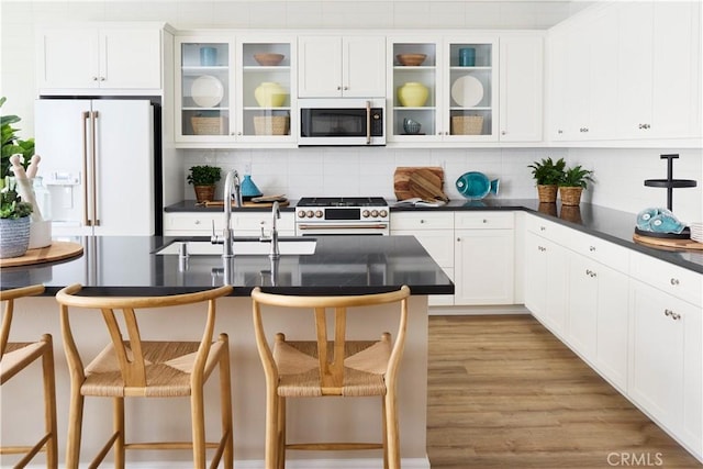 kitchen with tasteful backsplash, a breakfast bar, premium appliances, sink, and light hardwood / wood-style floors