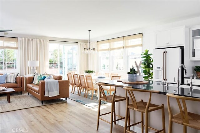 kitchen featuring a wealth of natural light, light hardwood / wood-style flooring, white cabinets, and high end white fridge