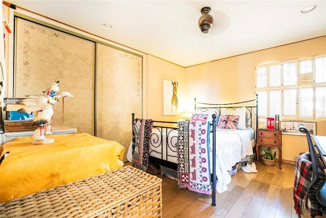 bedroom with hardwood / wood-style floors, ceiling fan, and a closet