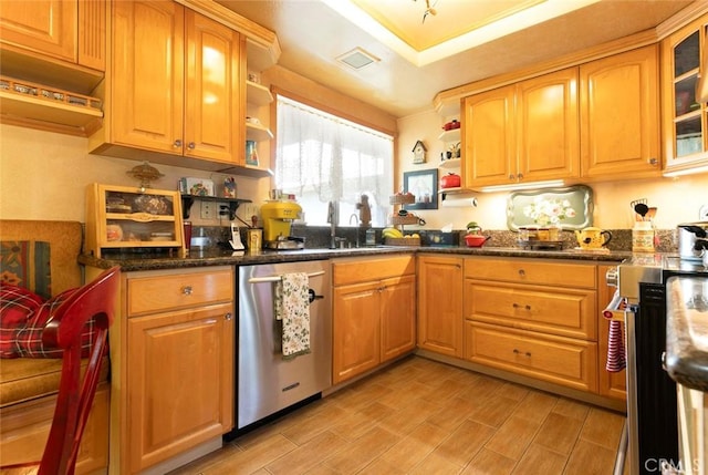 kitchen with dark stone countertops, sink, stainless steel appliances, and light hardwood / wood-style floors