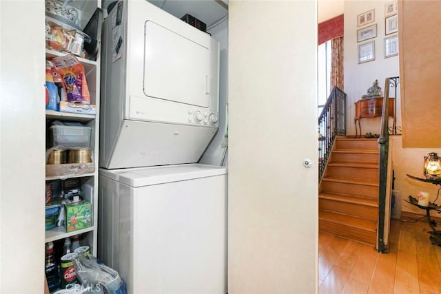 laundry area with stacked washer and dryer and light hardwood / wood-style floors