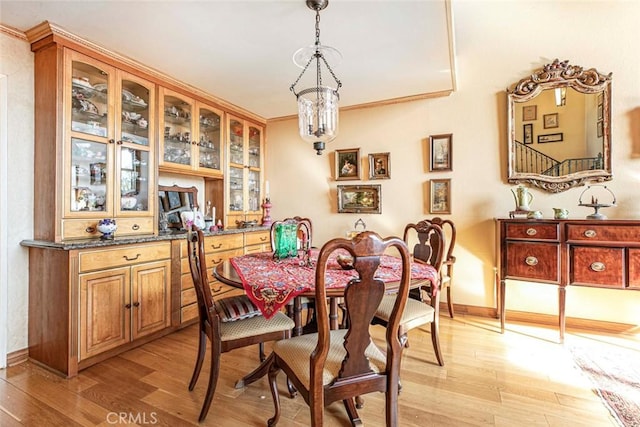 dining room featuring an inviting chandelier, light hardwood / wood-style flooring, and crown molding