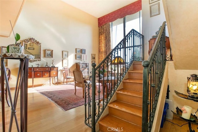 stairway with a towering ceiling and wood-type flooring