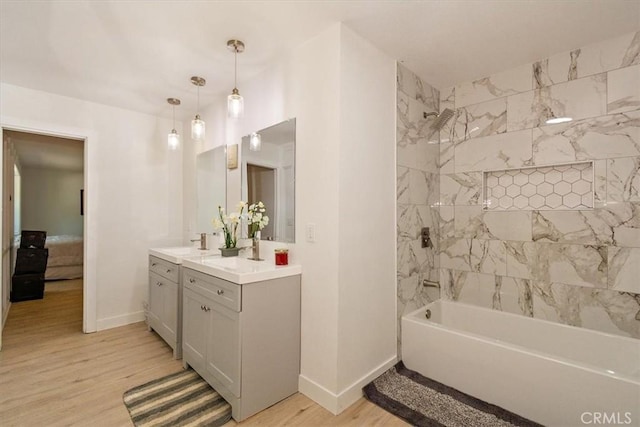 bathroom featuring hardwood / wood-style flooring, vanity, and tiled shower / bath