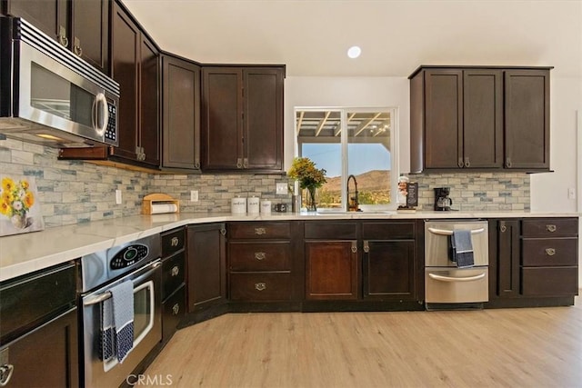 kitchen featuring appliances with stainless steel finishes, tasteful backsplash, dark brown cabinetry, and sink