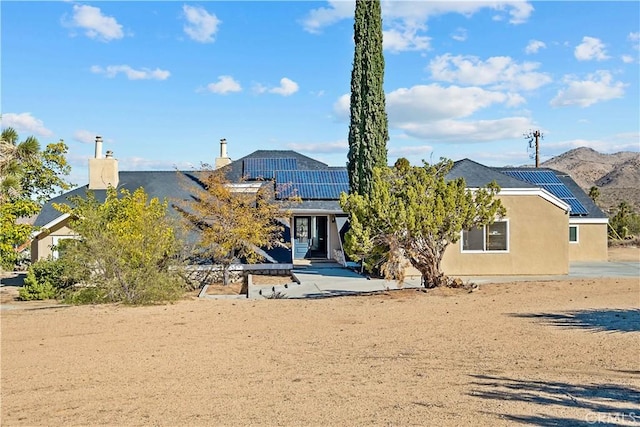 view of front facade featuring a patio area, a mountain view, and solar panels