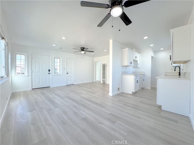 unfurnished living room featuring ceiling fan, light hardwood / wood-style flooring, and sink