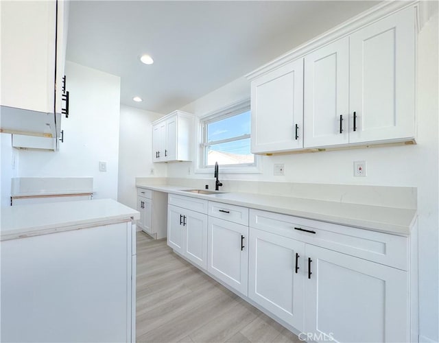 kitchen featuring white cabinets, light wood-type flooring, and sink