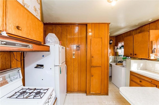 kitchen featuring white range with gas cooktop, washer / clothes dryer, wooden walls, and custom range hood