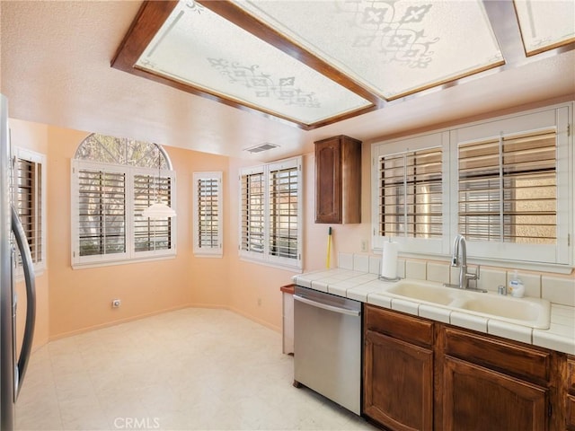 kitchen featuring tile countertops, sink, appliances with stainless steel finishes, and a textured ceiling