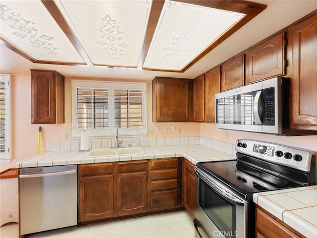 kitchen featuring tile countertops, sink, and appliances with stainless steel finishes