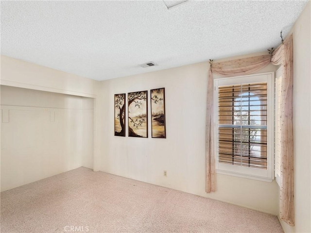 unfurnished room with carpet flooring and a textured ceiling