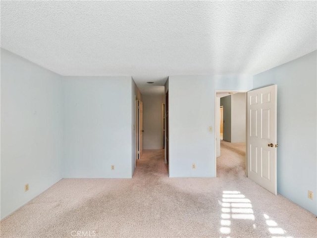 spare room with light carpet and a textured ceiling