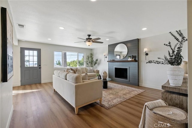 living room with ceiling fan, a fireplace, and hardwood / wood-style flooring