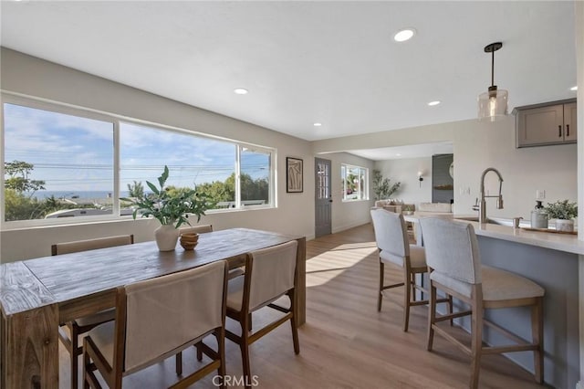 dining space featuring light wood-type flooring and sink