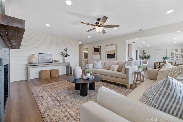 living room with wood-type flooring, ceiling fan, and wooden walls