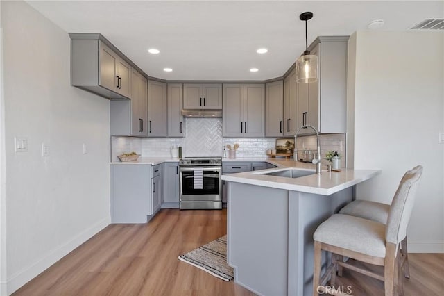 kitchen with gray cabinets, sink, stainless steel range with electric cooktop, and hanging light fixtures