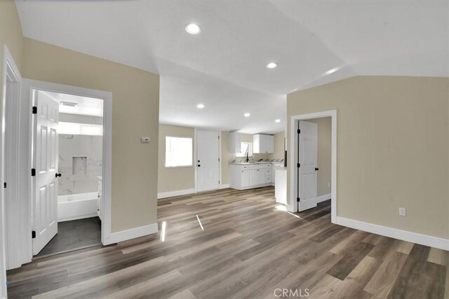 unfurnished living room featuring vaulted ceiling and dark hardwood / wood-style floors