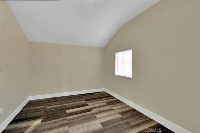 spare room featuring dark wood-type flooring and lofted ceiling