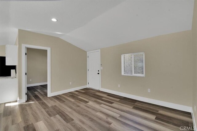 unfurnished room with hardwood / wood-style floors and lofted ceiling