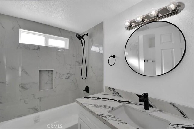 bathroom featuring tiled shower / bath combo and vanity