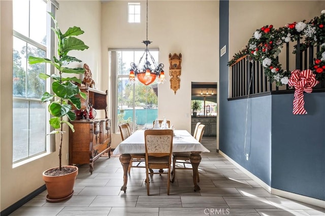 dining area featuring a towering ceiling, a wealth of natural light, and an inviting chandelier