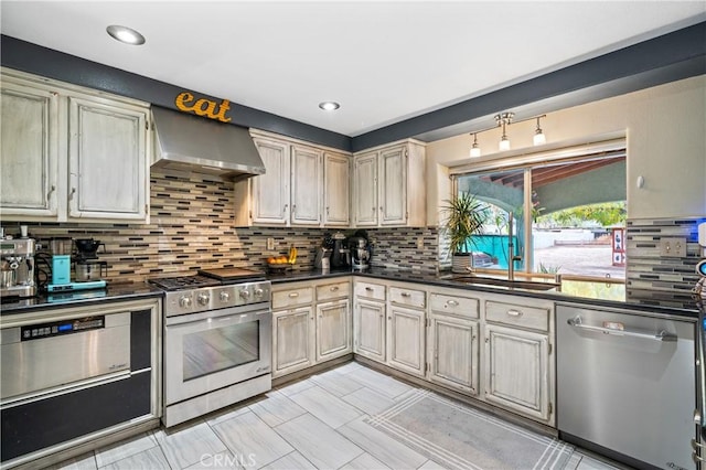 kitchen featuring appliances with stainless steel finishes, tasteful backsplash, wall chimney exhaust hood, sink, and cream cabinets