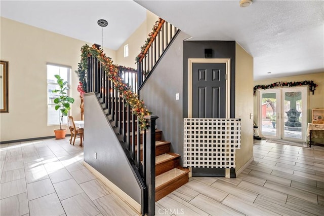 staircase with french doors and a textured ceiling