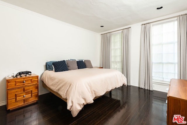 bedroom with crown molding and dark wood-type flooring