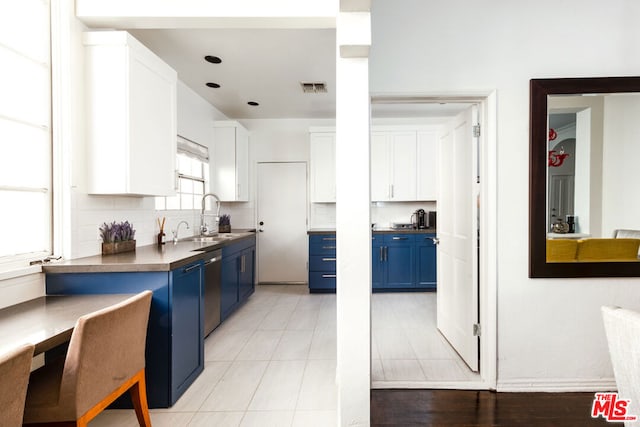 kitchen with dishwasher, white cabinets, blue cabinets, sink, and tasteful backsplash