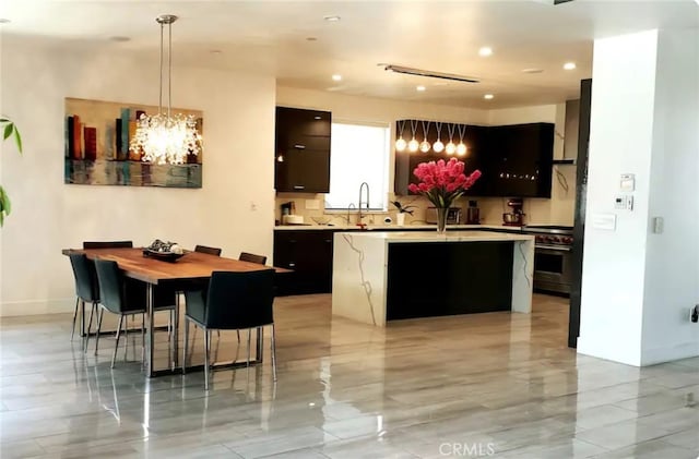 kitchen featuring decorative light fixtures, sink, a chandelier, high end stainless steel range oven, and a center island with sink