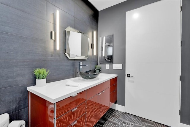 bathroom with toilet, tile walls, and vanity