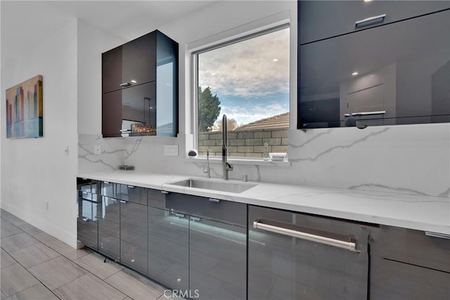 kitchen featuring light stone countertops, sink, stainless steel dishwasher, and tasteful backsplash