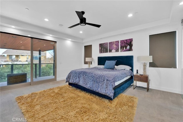 carpeted bedroom with ceiling fan and a tray ceiling