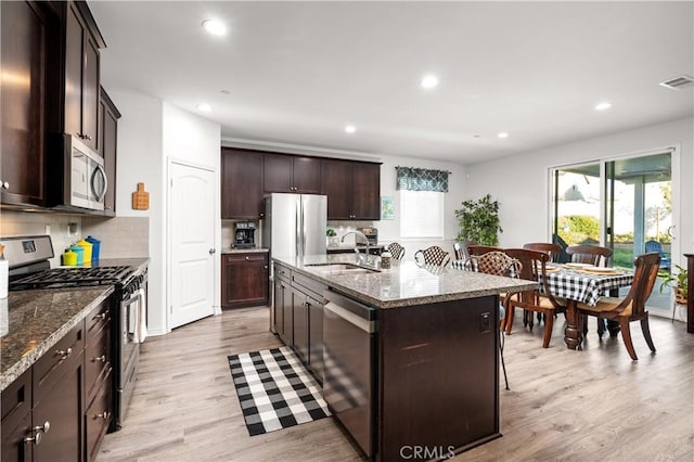 kitchen featuring stone countertops, appliances with stainless steel finishes, a kitchen island with sink, and sink