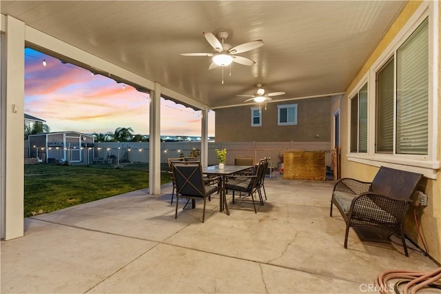 patio terrace at dusk with a lawn and ceiling fan