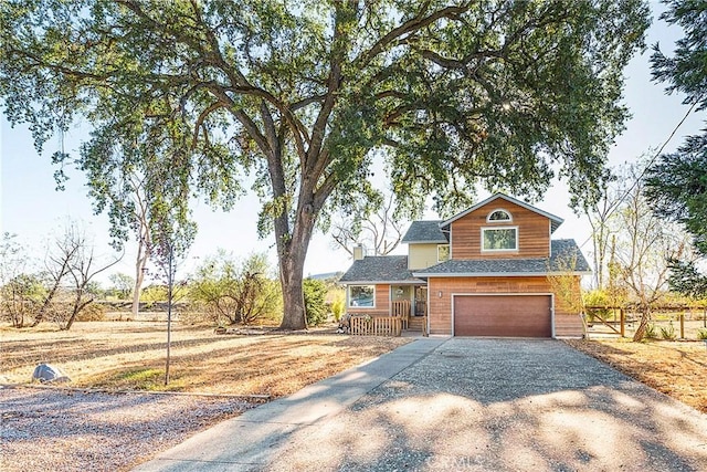 view of front facade with gravel driveway, an attached garage, and fence