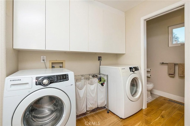 laundry room featuring washing machine and dryer and light wood-type flooring