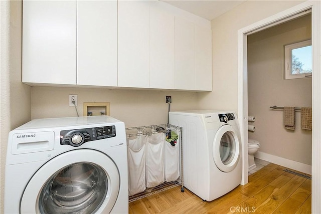 washroom with light wood-type flooring, visible vents, washer and clothes dryer, baseboards, and laundry area