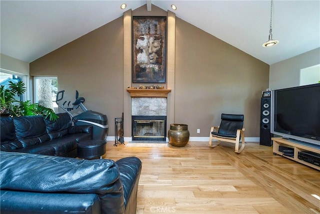 living room with a tile fireplace, hardwood / wood-style floors, and vaulted ceiling