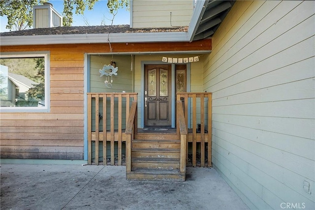 view of exterior entry featuring a porch and a chimney