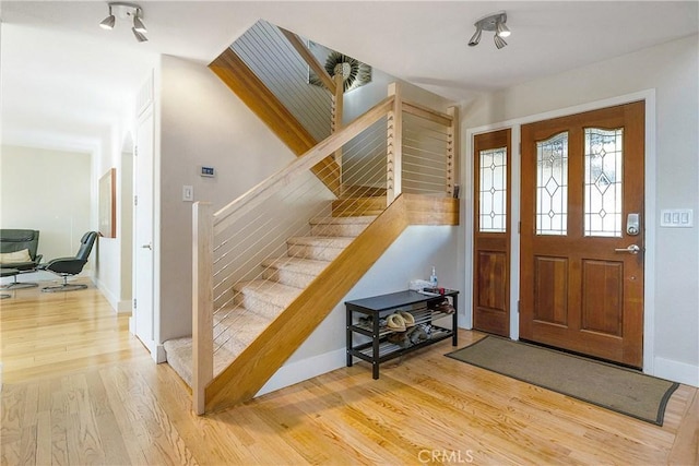 foyer featuring light wood finished floors, stairway, and baseboards