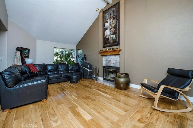 living room with hardwood / wood-style flooring, high vaulted ceiling, and a tiled fireplace