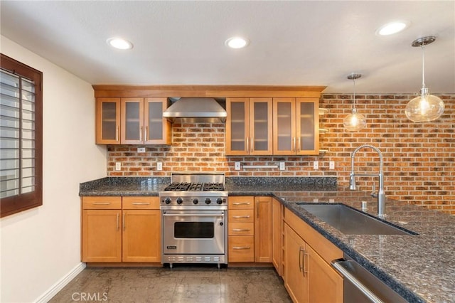 kitchen featuring sink, hanging light fixtures, wall chimney exhaust hood, dark stone countertops, and appliances with stainless steel finishes