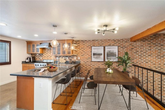 kitchen featuring hardwood / wood-style floors, dark stone counters, a kitchen breakfast bar, decorative light fixtures, and brick wall