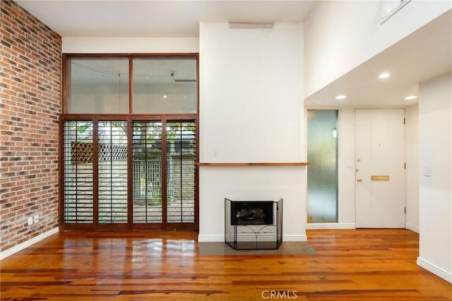 unfurnished living room featuring hardwood / wood-style flooring and brick wall