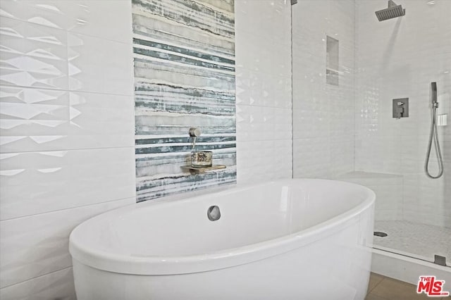 bathroom featuring separate shower and tub and tile walls