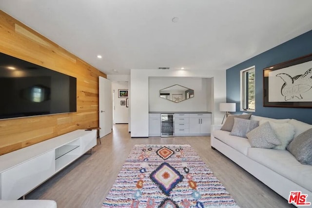 living room featuring wood walls, beverage cooler, and light wood-type flooring