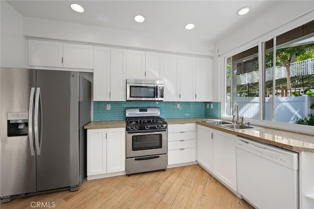 kitchen with white cabinetry, sink, stainless steel appliances, and light hardwood / wood-style flooring