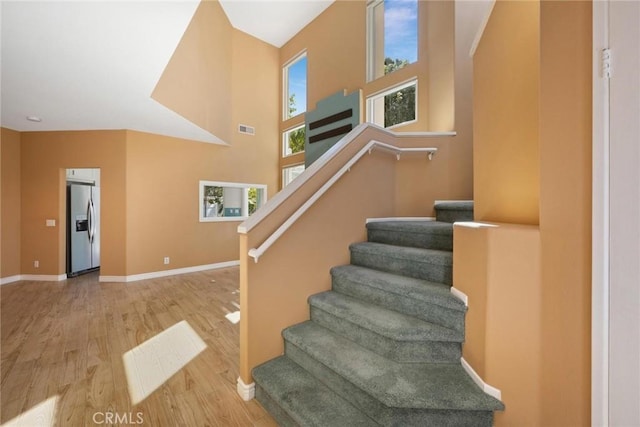 staircase featuring a high ceiling and hardwood / wood-style flooring